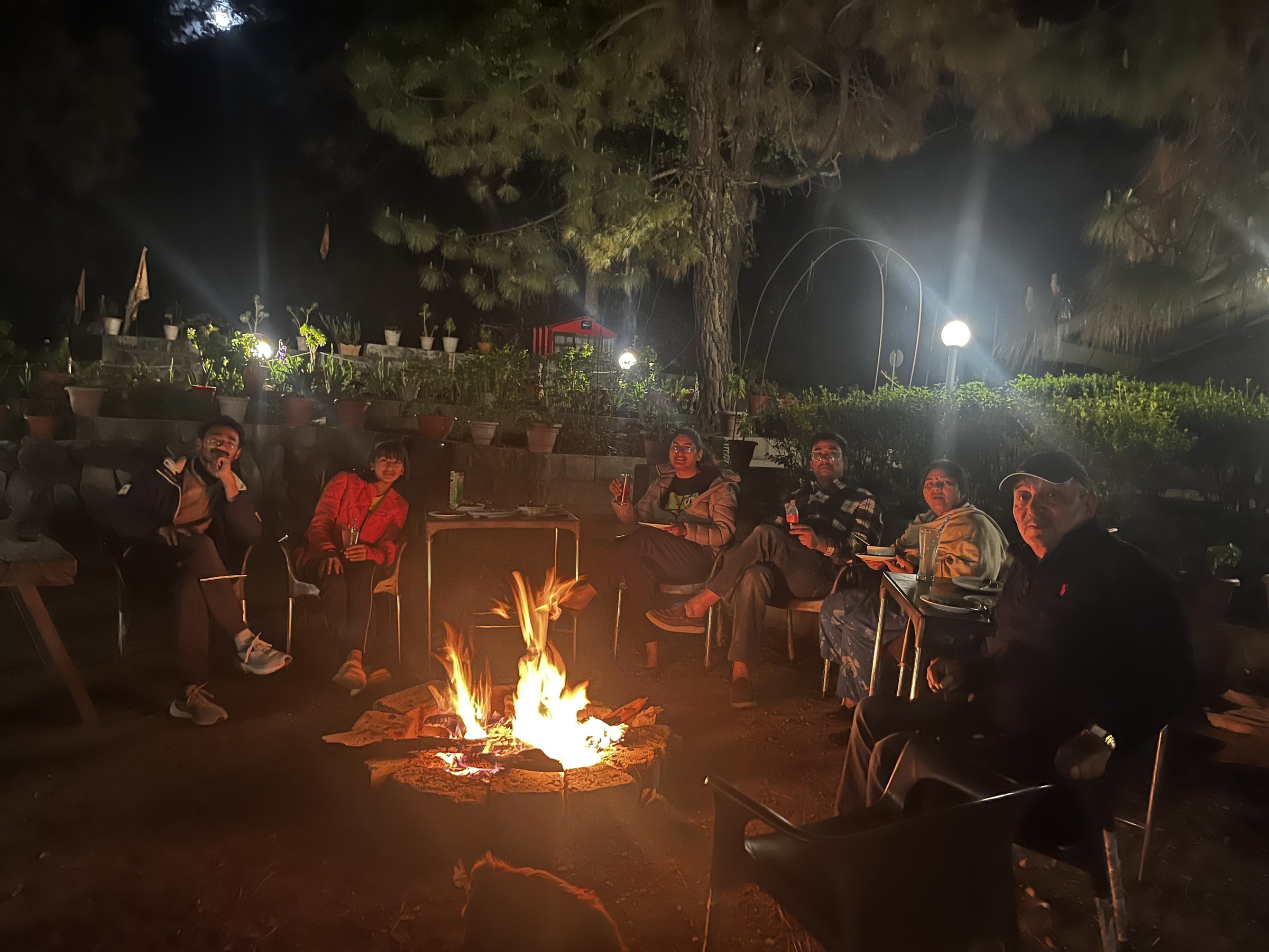 Family and guests sitting around a glowing bonfire at night at The Glide Inn