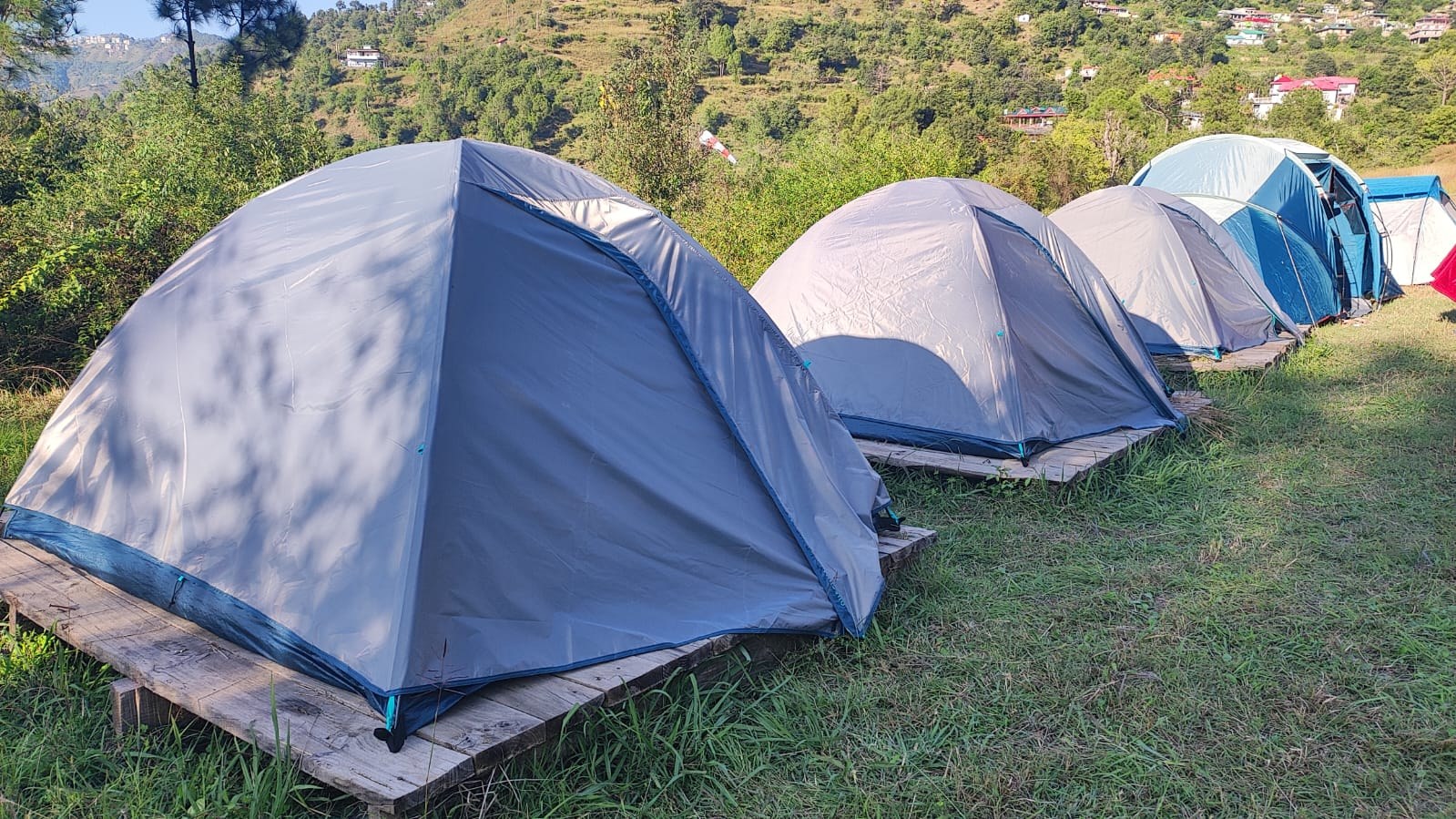Row of grey dome tents on elevated wooden platforms at The Glide Inn camping resort